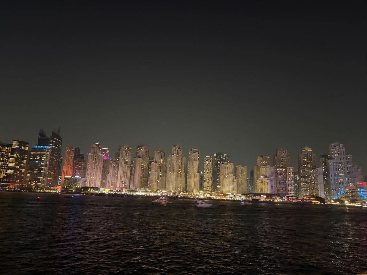 The lit JBR and Dubai Marina skyline at night, seen from the water with small craft in the foreground